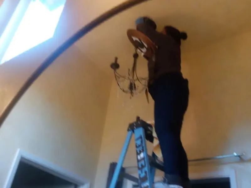 Electrician installing a chandelier in a Charles City residence